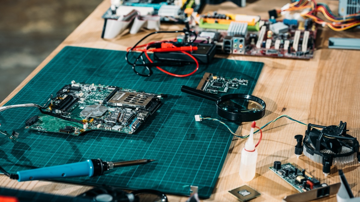 Circuit boards, a soldering iron and components on an electronics workbench