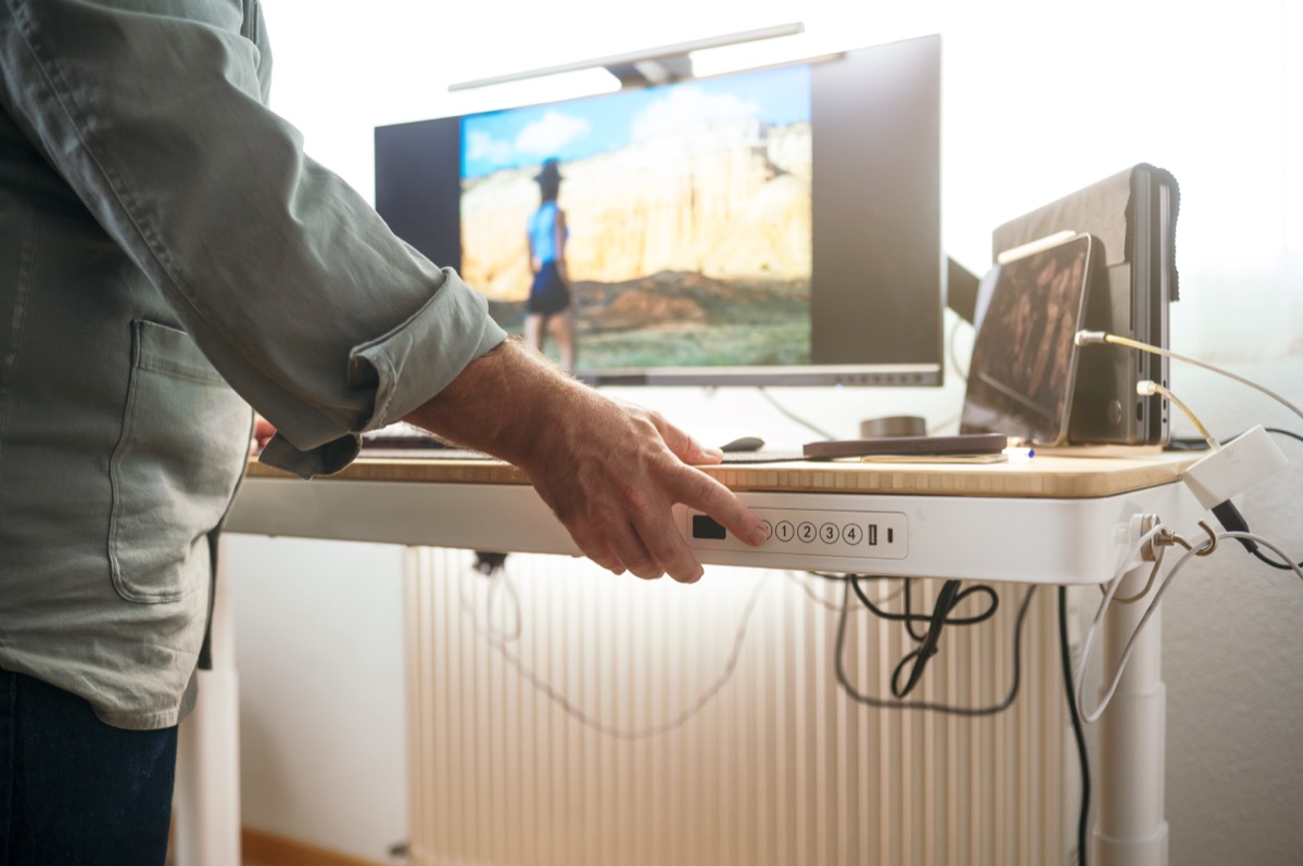 Standing at a height-adjustable desk with a mat underfoot