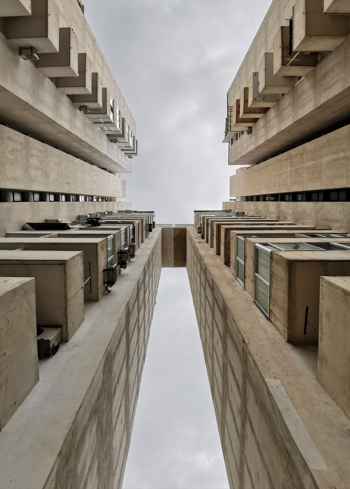 Symmetrical concrete apartment buildings with exposed geometric balconies and raw structural elements