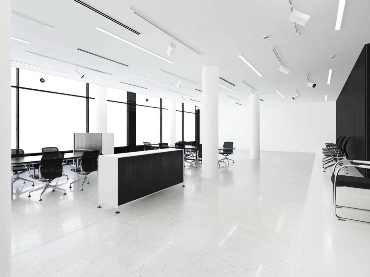 Minimalist white office space with black accents, floor-to-ceiling windows, and modern workstations
